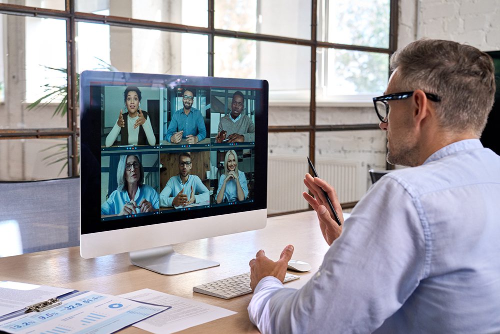 Corporate leader manager leading videoconference with diverse team business people having digital group video call conference working in office at online virtual meeting on pc computer. Over shoulder